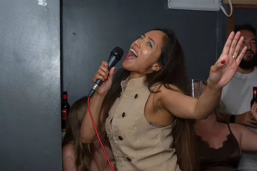 A singer with a hand raised in one of the private karaoke rooms